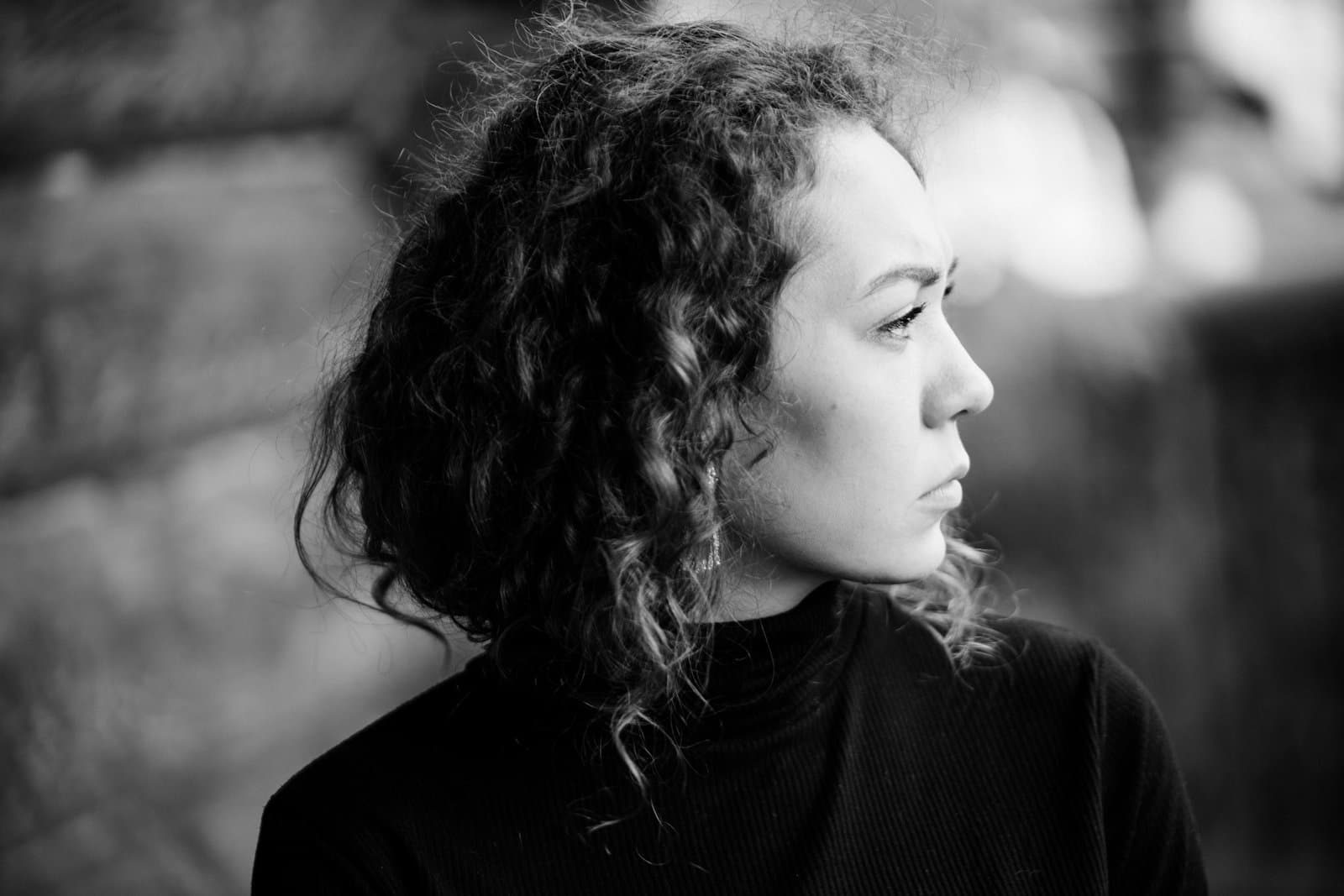 A woman with dark curly hair looking away in thought