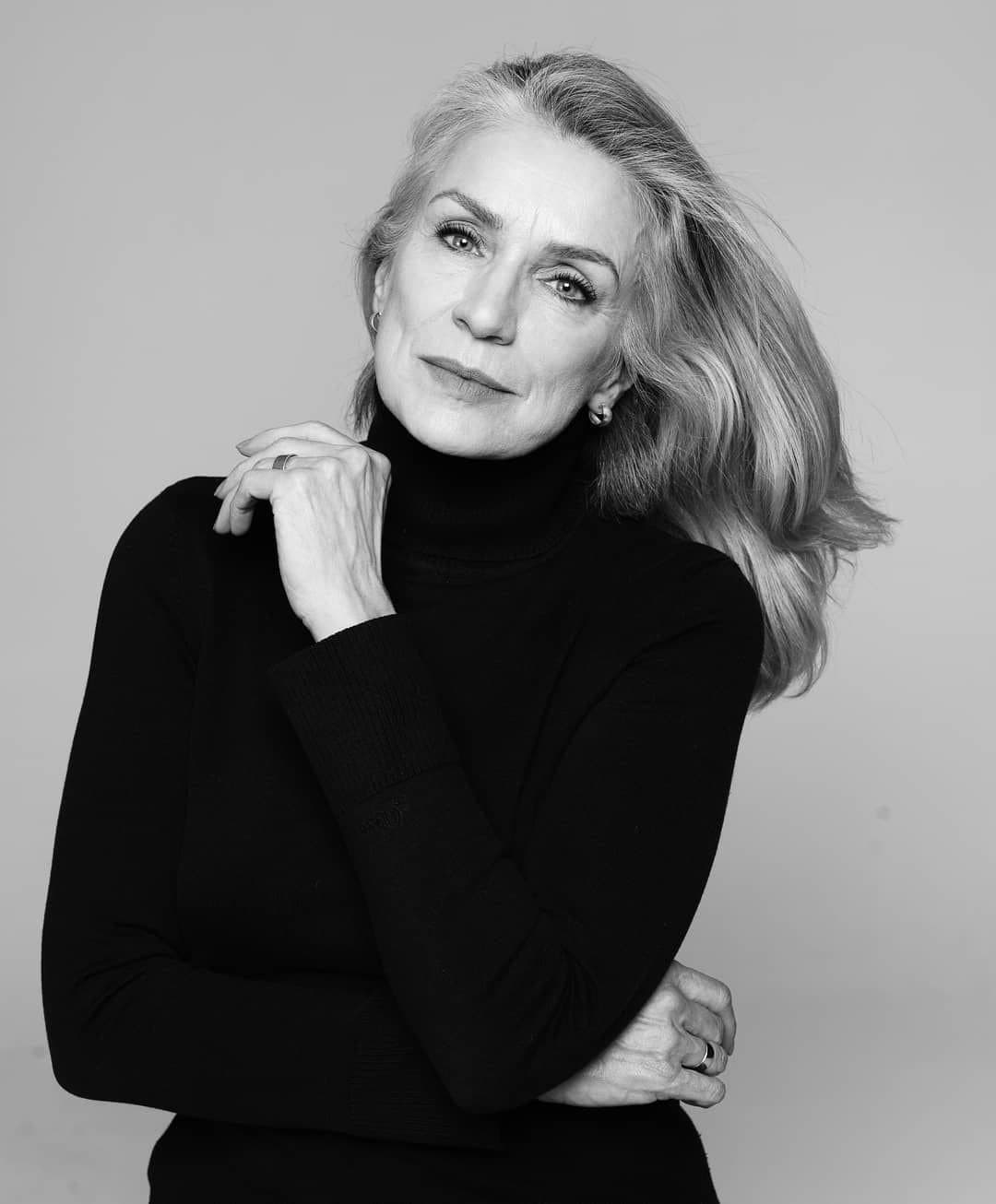 A woman with shoulder-length grey hair in a black turtleneck